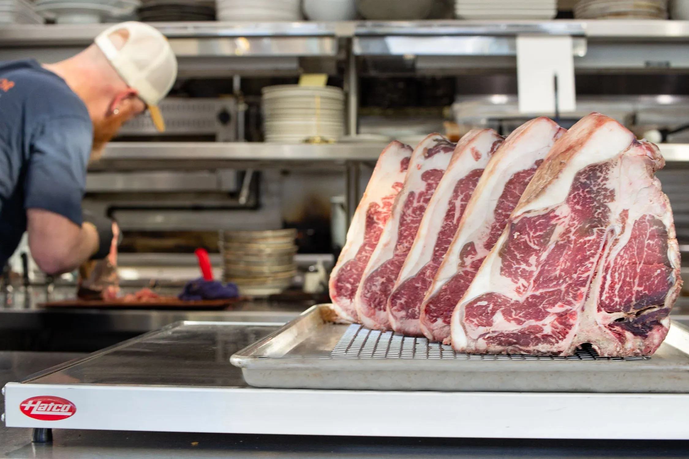 Chef and Owner Thad Lyman working in the open kitchen with dry-aged steaks