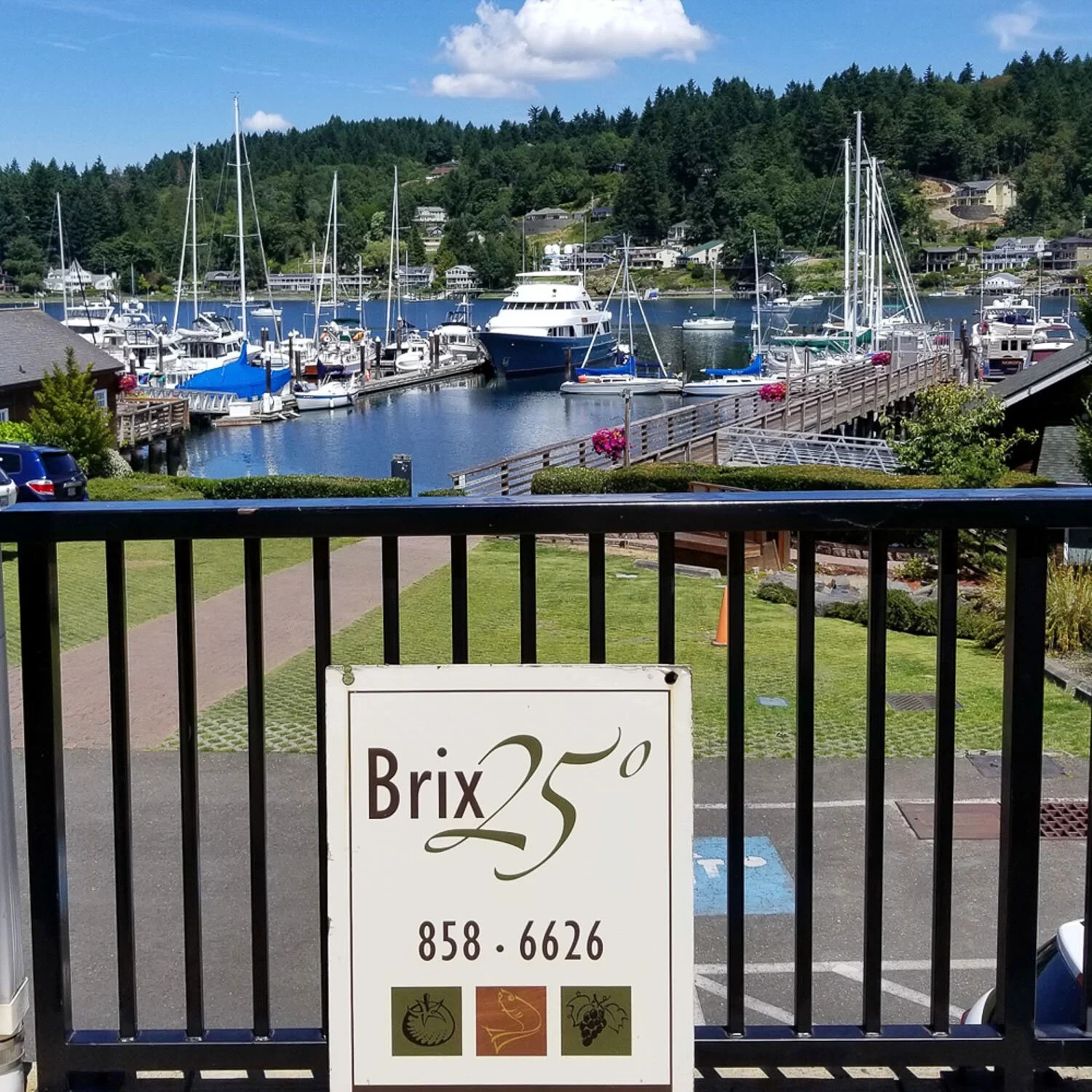 The Brix 25° sign on the railing above the Gig Harbor marina on a bright day