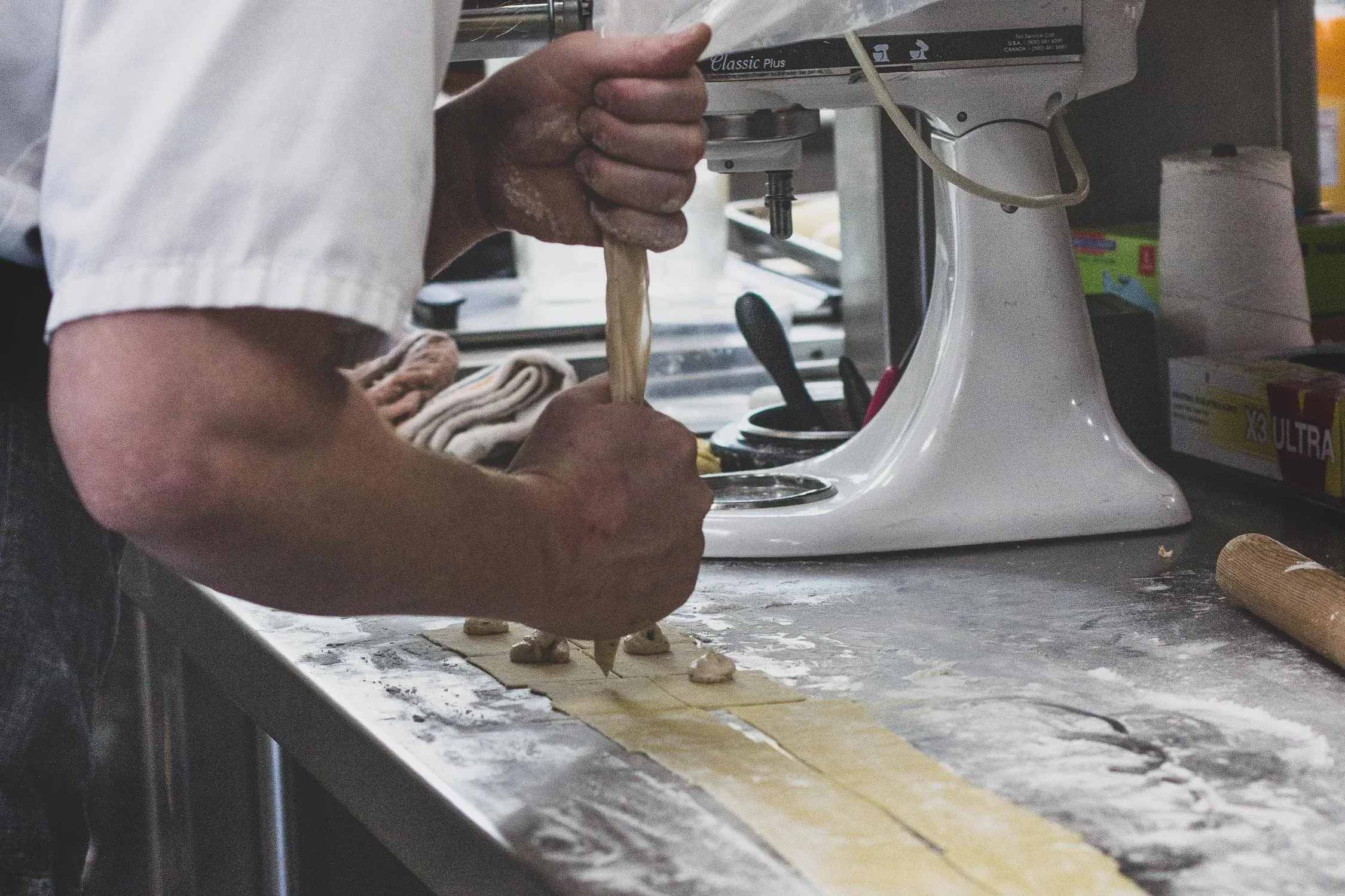 Hands rolling out fresh pasta dough in the Brix 25° kitchen